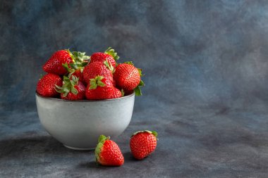 Strawberries and blueberries in a cup, on a wooden table. Blurred background. Rustic style. Healthy diet.