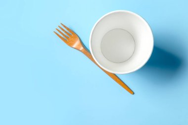Açık mavi arka planda tek kullanımlık kağıt bardak. Tek kullanımlık sofra takımı. Kavram.