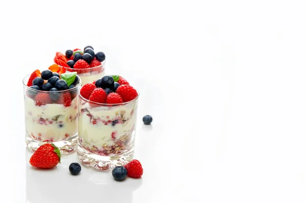 Muesli con yogur y bayas en un vaso Sobre un fondo blanco. Proceso de preparación de postres. Comida fitness. Copiar espacio. — Foto de Stock