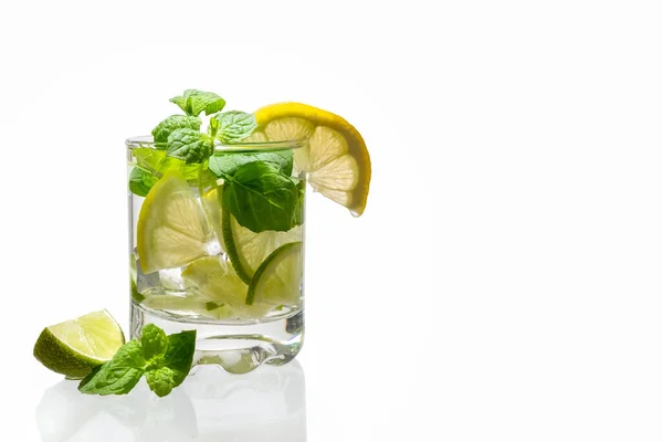 Citronnade d'agrumes avec glace dans un verre décoré de tranches de citron, citron vert et menthe et sur un fond blanc. Boisson fraîche d'été. Désintoxication. Aliments sains riches en vitamines et antioxydants. Espace de copie — Photo