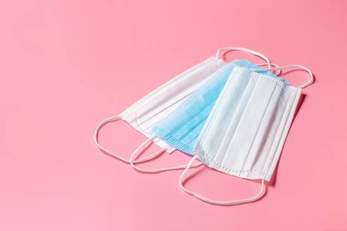 Masada tek kullanımlık ameliyat maskeleri var. Pembe arka plan. Yukarıdan bak. Metnin için yer.