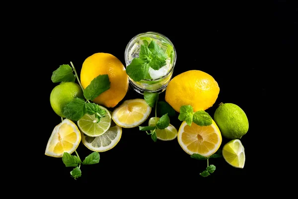 Limonada cítrica con limón, lima y hielo en un vaso sobre fondo negro. Salpicadura. Vista desde arriba — Foto de Stock