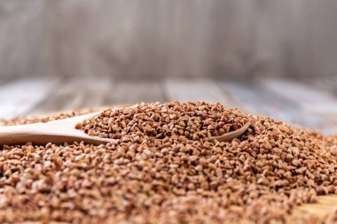 Dağınık karabuğday. Tahta bir kaşıkta karabuğday, ahşap bir masada yatar. Sağlıklı beslenme. Diyet yemek. Detoks. Yakın plan..