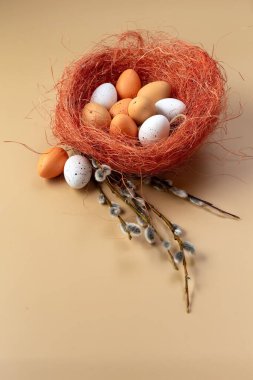Easter colorful eggs in a basket and branches of pussy willow on a beige background. Colored eggs. Easter still life. Wooden background. Place for your text. High quality photo