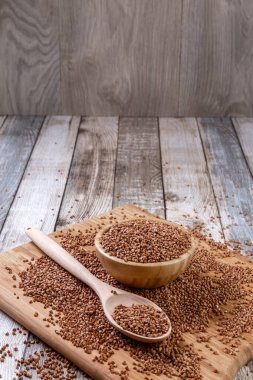 Dağınık karabuğday. Tahta bir kasede karabuğday ve kaşık tahta bir masanın üzerinde yatıyor. Dağınık karabuğday. Sağlıklı beslenme. Diyet yemek. Uzayı kopyala Yakın plan. Yüksek kalite fotoğraf