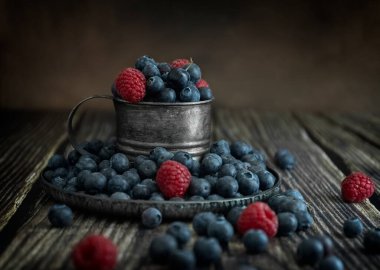 Böğürtlen ve ahududu eskimiş bir fincanda koyu bir arka planda. Klasik metal bardak. Fotoğraf taşra tarzında. Uzayı kopyala Yüksek kalite fotoğraf