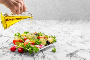 Tabakta taze sebzeler ve salata kasesi. El, şişeden zeytinyağı döker. Sağlıklı beslenme. Vejetaryen yemeği. Sağlıklı beslenme. Yüksek kalite fotoğraf