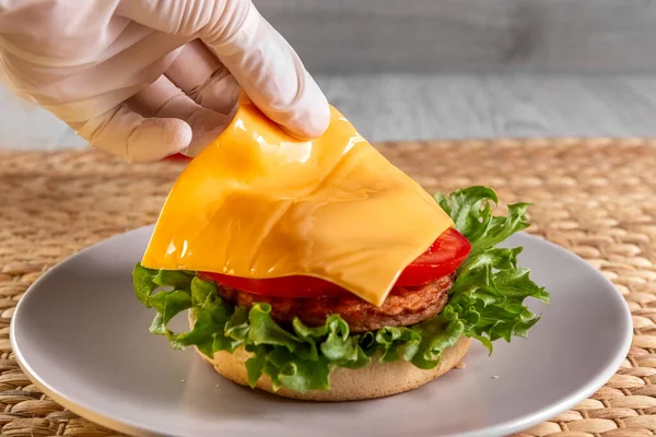 Delicious and healthy burger for lunch and breakfast. The process of making a burger. The hand of the chef prepares a burger. Homemade recipe. Fast food. Concept. High quality photo