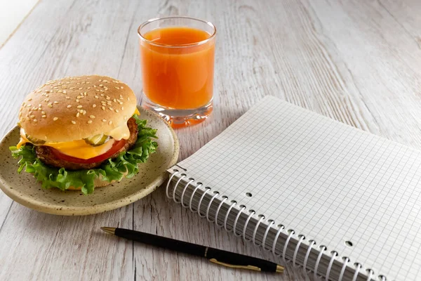 A quick snack for businessmen, schoolchildren, students. Notebook, Delicious and healthy burger and fruit juice. Fast food. Student lunch. Concept. Copy space. High quality photo