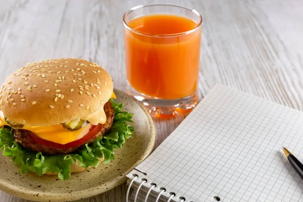 A quick snack for businessmen, schoolchildren, students. Notebook, Delicious and healthy burger and fruit juice. Fast food. Student lunch. Concept. Copy space. High quality photo