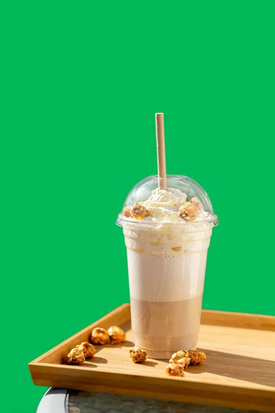 Krem şantili ve yeşil arka planda patlamış mısır aromalı frappe. Tek kullanımlık plastik bardakta kapaklı frappe. Götürün..