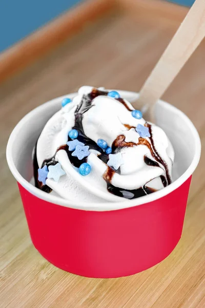 White Ice cream with chocolate sauce in a paper bowl. Ice cream in a red paper cup. Take away.