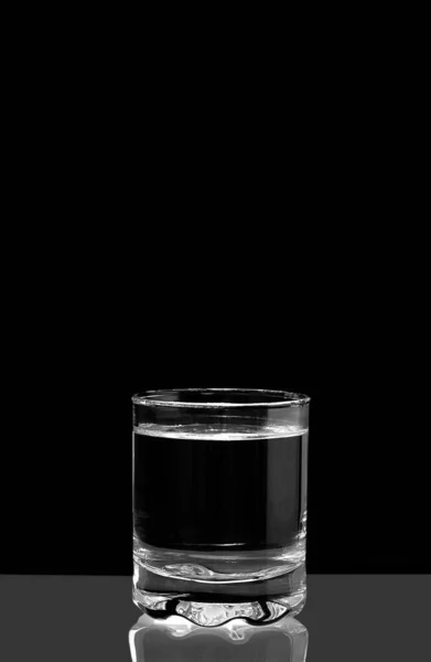 Чистая вода в стакане. Полный стакан воды на черном фоне. Черно-белая фотография. Концепция. — стоковое фото