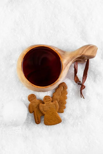 Kuksa con té y galletas de jengibre en la nieve. Copa de madera tradicional finlandesa. Puesta plana. Fotos De Stock
