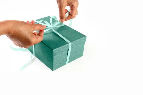 手正在把辫子绑在礼品盒上.礼物包装。打开礼物的包装白色背景。概念。隔离。横幅. — 图库照片