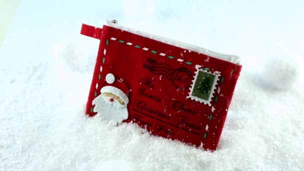 Червоний декоративний конверт для Санта Клауса і снігові кульки в снігу. Сніг.. — стокове відео