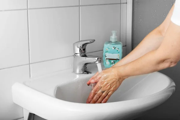 The woman washes her hands in the sink. Hygiene and cleanliness concept. — Stock Photo, Image