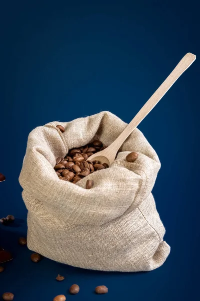 Grãos de café em um saco de lona em um fundo azul escuro. Conceito. — Fotografia de Stock