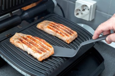 Şef elektrikli ızgarada alabalık hazırlıyor. Sağlıklı yiyecekler. Şefin eli. Ev yapımı yemek..