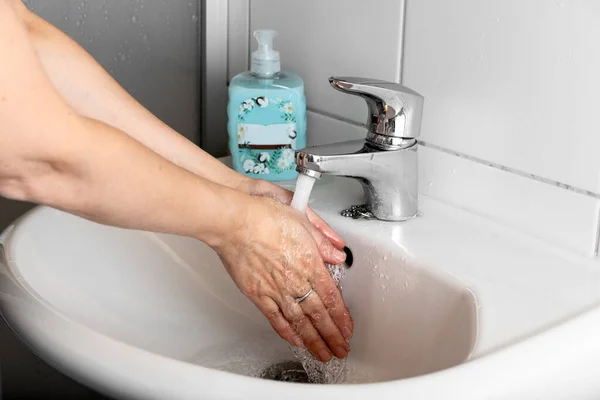女は流しの中で手を洗う。衛生と清潔の概念. — ストック写真
