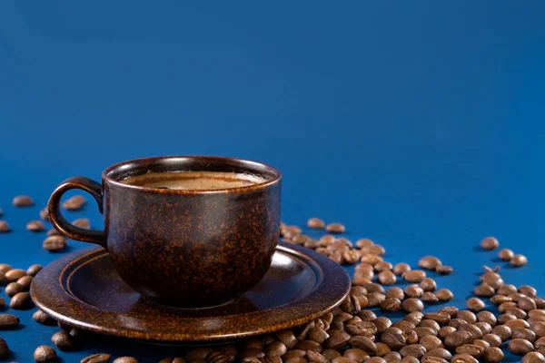 Xícara marrom com grãos de café e café em um fundo azul. Conceito. Espaço de cópia. — Fotografia de Stock