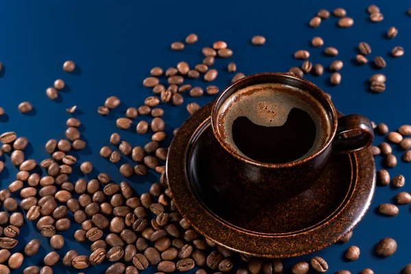 Xícara marrom com grãos de café e café em um fundo azul. Conceito. Espaço de cópia. — Fotografia de Stock