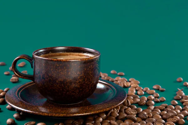 Xícara marrom com grãos de café e café em um fundo verde. Conceito. Espaço de cópia. — Fotografia de Stock