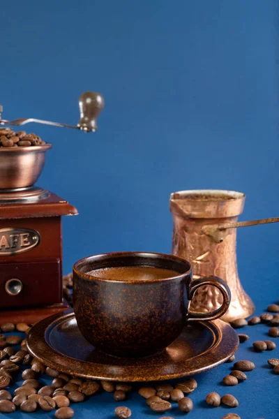 Tasse mit Kaffee, Kupfertürke und manueller Kaffeemühle mit Kaffeebohnen auf blauem Hintergrund. — Stockfoto