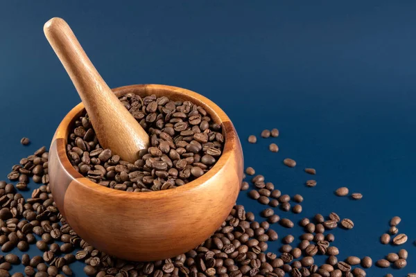 Ziarna kawy w drewnianej zaprawie. Ręczna młynek do kawy na niebieskim tle. Przestrzeń kopiowania — Zdjęcie stockowe