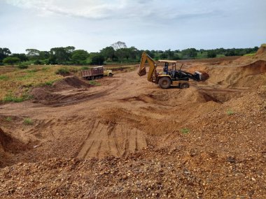 Imagen de una cantera, al costado izquierdo la ilustracion de una volqueta sencilla sobre ruedas, al costado derecho la ilustracion de un retrocargador model o 416c aubre ruedas propulsado por un motor diesel,