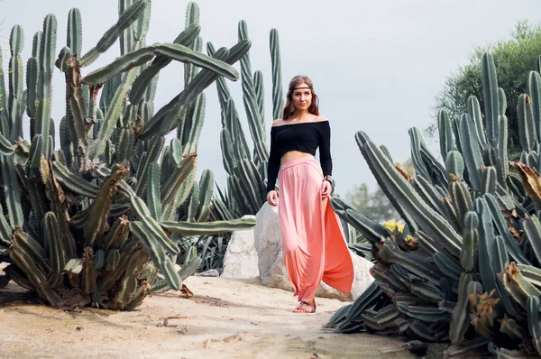 Hippie žena v dlouhou růžovou sukni kousek od velké kaktusy — Stock fotografie