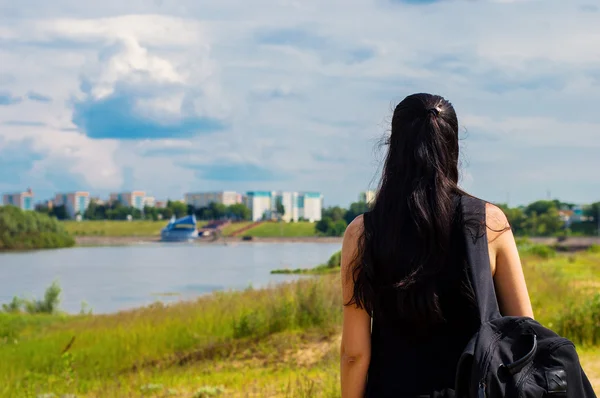 Joven viajero morena con mochila negra mirando sobre una ciudad — Foto de Stock