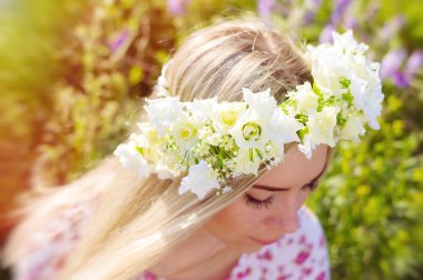 Genç bir sarışın kızın kafasına çiçek taç