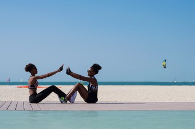 İki Afrikalı kız Bae'deki Dubai plajında egzersiz yapıyor. Sağlıklı yaşam tarzı ve açık hava aktivite konsepti