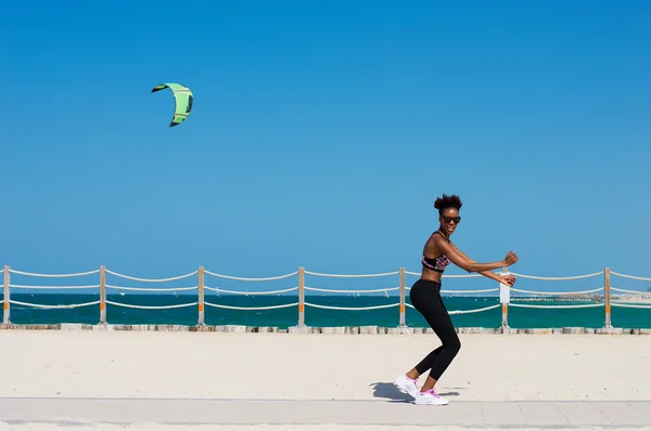 Egy afrikai nő, jogging, Egyesült Arab Emírségek Dubai tengerpartján. Fiatal afrikai nő birtoklás móka a tengerparton — Stock Fotó