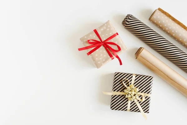 Kraft kağıdına sarılı iki Noel hediyesi kutusu ve DIY için kağıt rulo beyaz arka planda sarılı hediyeler, düz konum