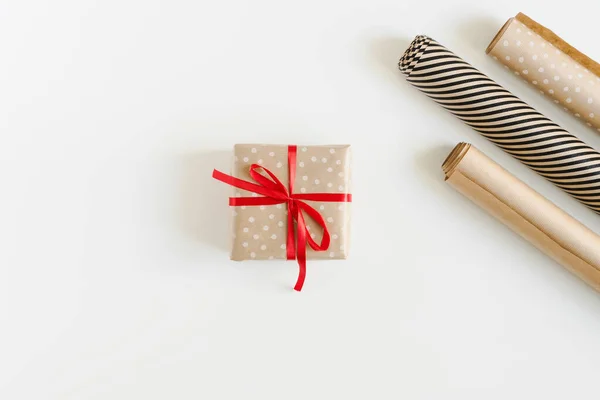 礼品盒用波尔卡圆点牛皮纸包裹 白色桌子上有红丝带和纸卷 顶部尽收眼底 环保圣诞礼物包装理念 — 图库照片
