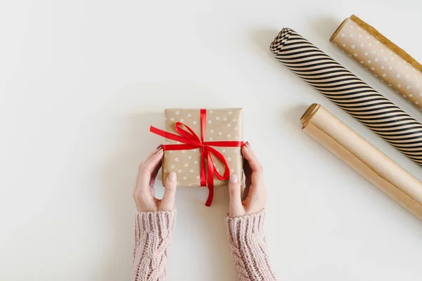 Frauenhände Halten Eine Kleine Weihnachtsgeschenkschachtel Die Kraftpapier Mit Roter Schleife — Stockfoto
