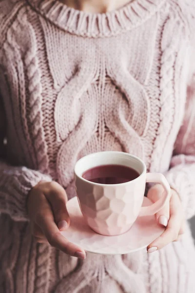 Female in warm knitted sweater holding a cup of Hibiscus tea. Red tea. Hot herbal drink