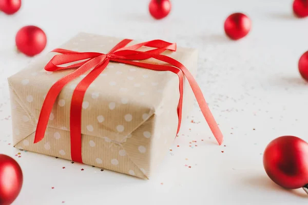 圣诞礼品盒 用波尔卡圆点牛皮纸包裹 红色缎带 红色圣诞球和白色背景的小亮晶晶 节日期间 礼品包装的主意 — 图库照片