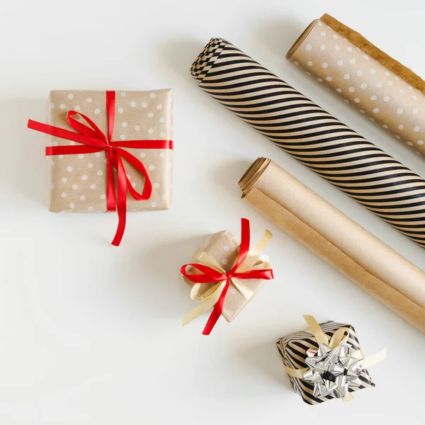 三个礼品盒包裹在牛皮纸和纸卷上 白色背景 顶视图 圣诞礼物包装 — 图库照片