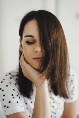 Kahverengi saçlı, dalgın bakışlı genç bir kadının kapalı bir portresi.