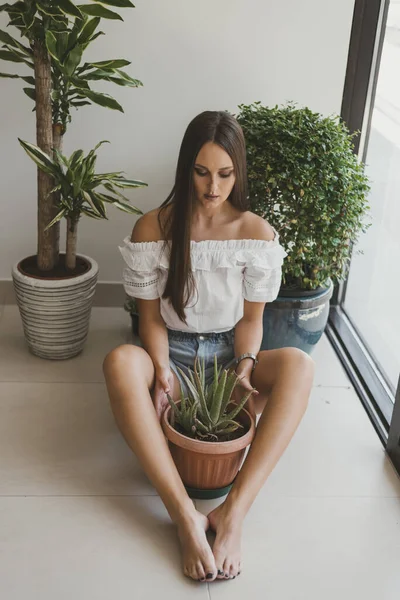Jovem Mulher Sentada Chão Seu Apartamento Segurando Pote Com Planta — Fotografia de Stock