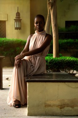 Yeşil çalılar yakınındaki bir bankta oturan kadın