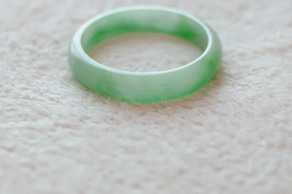 Pulseira verde sobre tecido branco — Fotografia de Stock