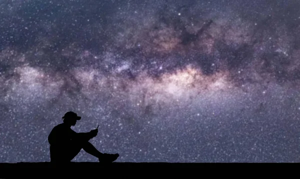 Силуэт Человека Кепке Сидящего Использующего Мобильный Телефон Ярком Звездном Фоне — стоковое фото