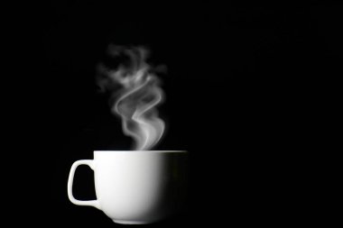 Kahve fincanından siyah arka planda buhar çıkıyor.