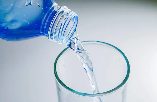 把瓶子里干净的饮用水倒进杯子里 — 图库照片