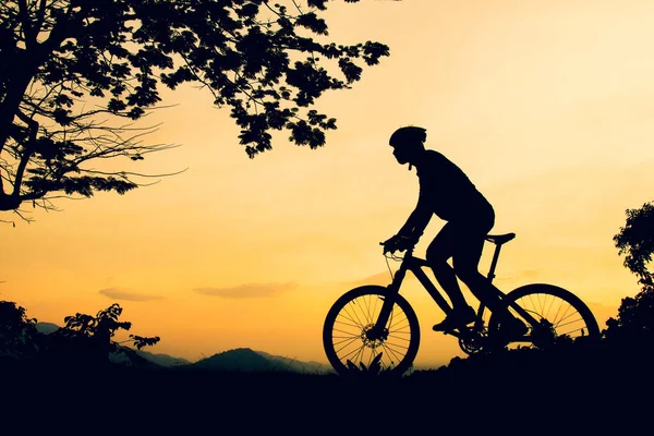 A silhouette of a mountain biking practicing bicycles on a high mountain