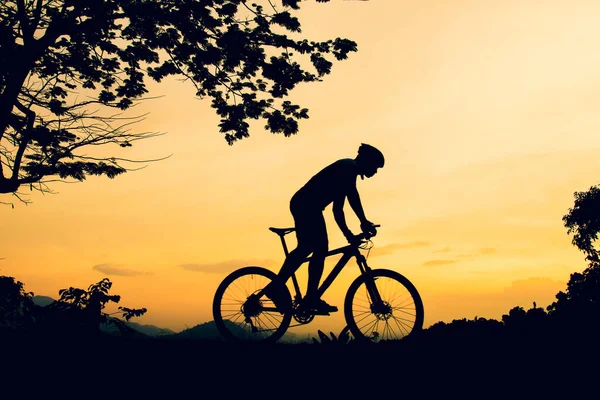 A silhouette of a mountain biking practicing bicycles on a high mountain